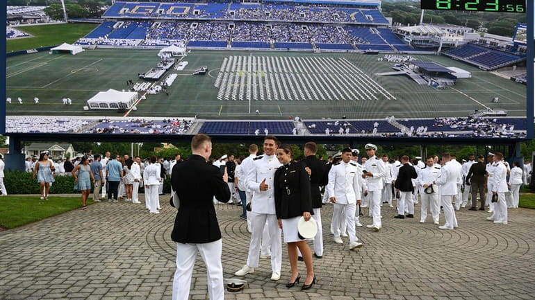 Graduating midshipmen gather under the scoreboard to line up for...
