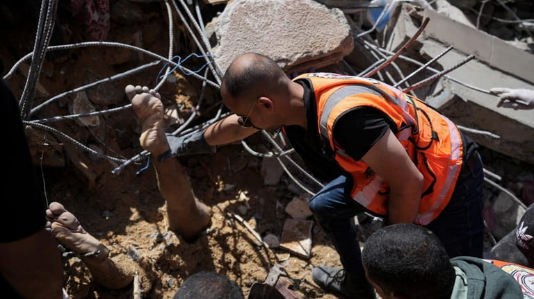Palestinians rescuers dig around the body of man in the...