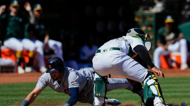 Detroit Tigers' Matt Vierling, left, scores next to Oakland Athletics...