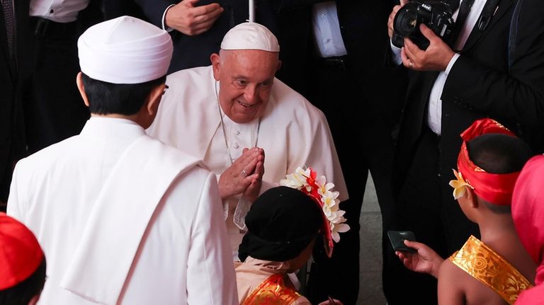 Pope Francis, center, accompanied by the grand imam of Istiqlal...