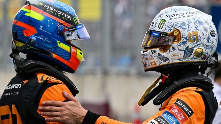 McLaren driver Lando Norris of Britain, right, shakes hands with...