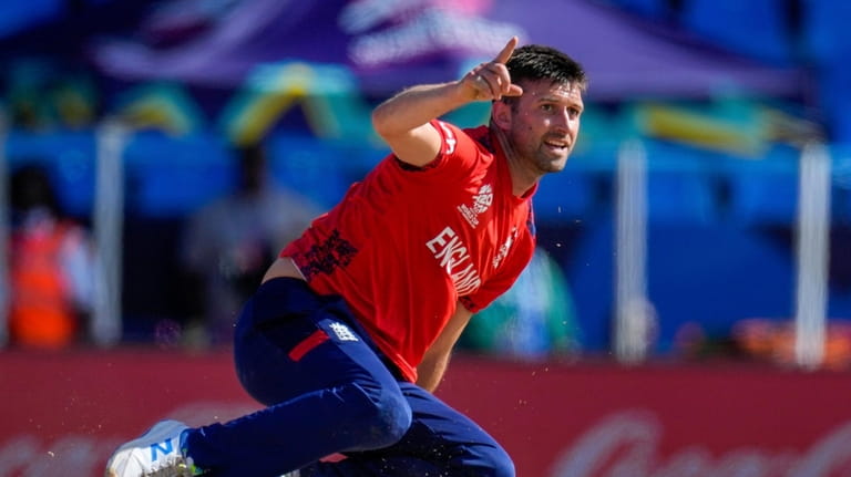 England's Mark Wood celebrates after taking the wicket of Oman's...