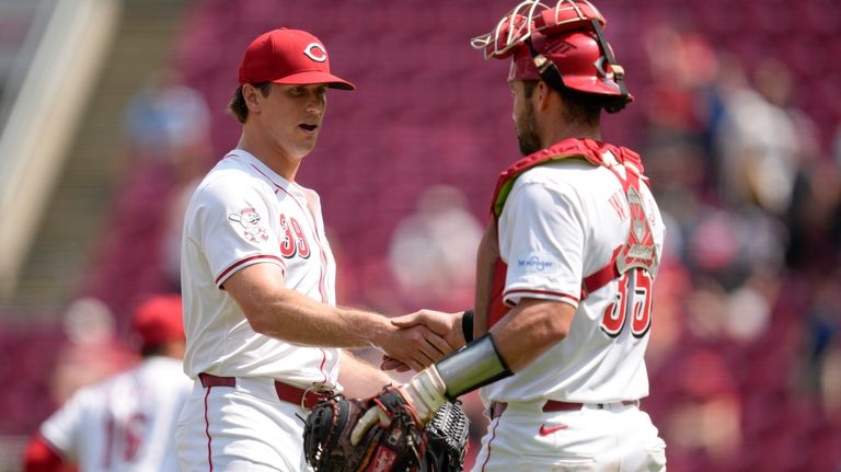 Cincinnati Reds' Lucas Sims, left, celebrates with Austin Wynns, right,...