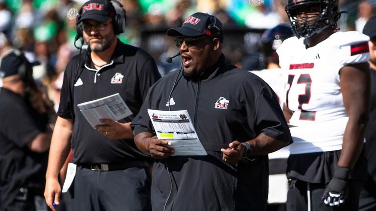 Northern Illinois head coach Thomas Hammock, center, talks into his...