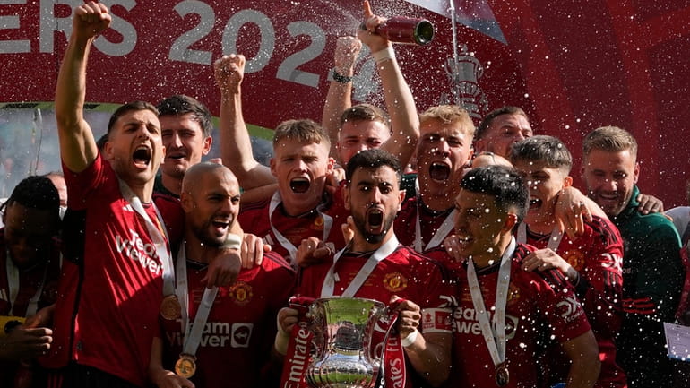 Manchester United's Bruno Fernandes holds the trophy after his team...