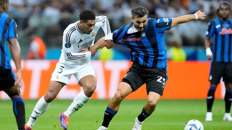 Real Madrid's Jude Bellingham, center left, fights for the ball...