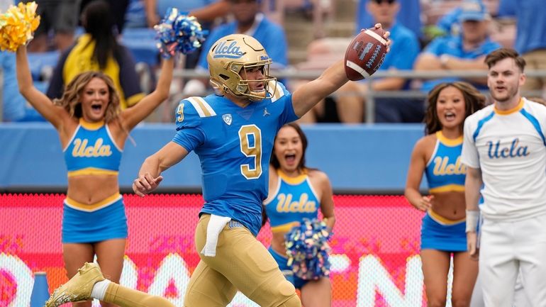 UCLA quarterback Collin Schlee celebrates as he scores a touchdown...