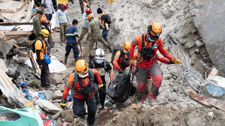 Rescuers carry a body from the landslide-hit village of Masara...