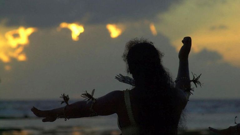 A Kiribati dancer raises her arms as she welcomes the...