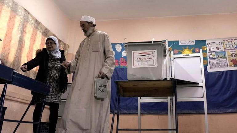 An elderly man is helped after casting his vote for...