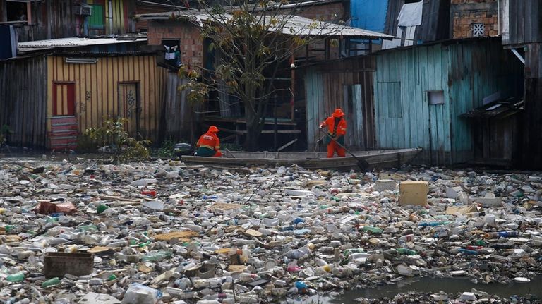 City workers remove garbage floating on the Negro River, which...