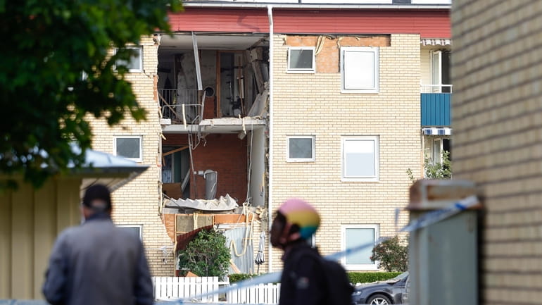 People look at the damages caused by an explosion in...