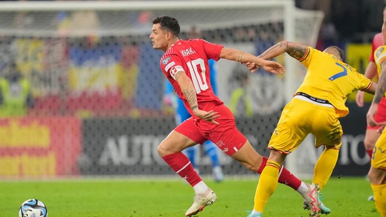 Switzerland's Granit Xhaka, left, is tackled by Romania's Denis Alibec...