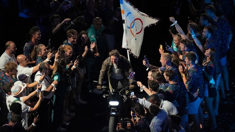 Tom Cruise rides a motorbike during the 2024 Summer Olympics...