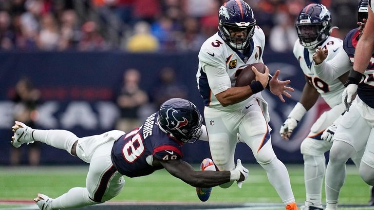 Denver Broncos quarterback Russell Wilson (3) tries to get past...