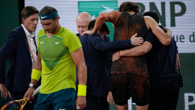 Germany's Alexander Zverev is carried off the court after twisting...