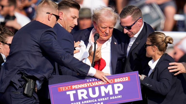 Republican presidential candidate former President Donald Trump is helped off...