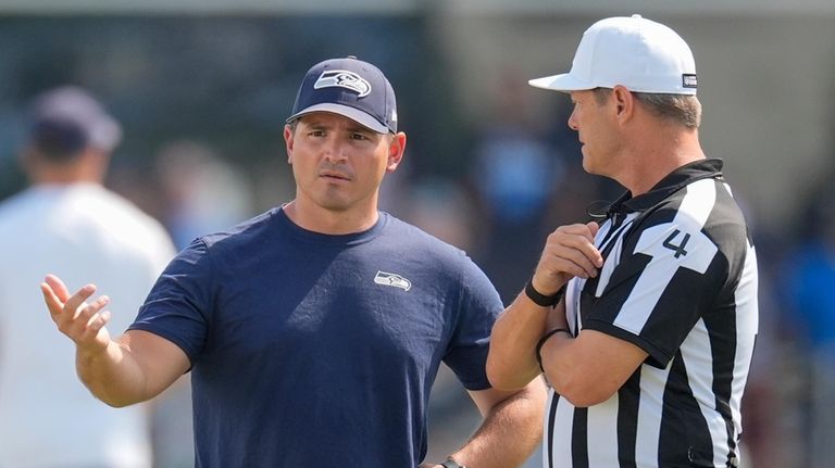 Seattle Seahawks head coach Mike Macdonald, left, speaks with an...