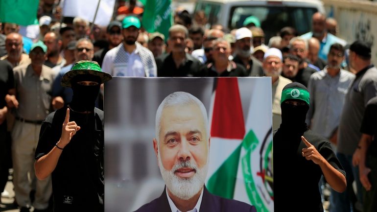 Hamas members hold a poster of Hamas political chief Ismail...