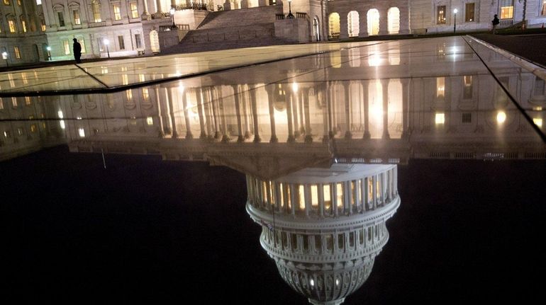 The U.S. Capitol dome is reflected before sunrise in Washington,...