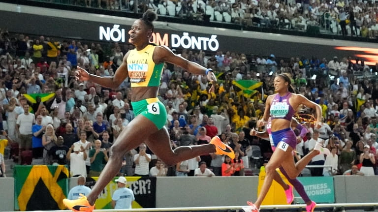 Shericka Jackson, of Jamaica, crosses the line to win the...