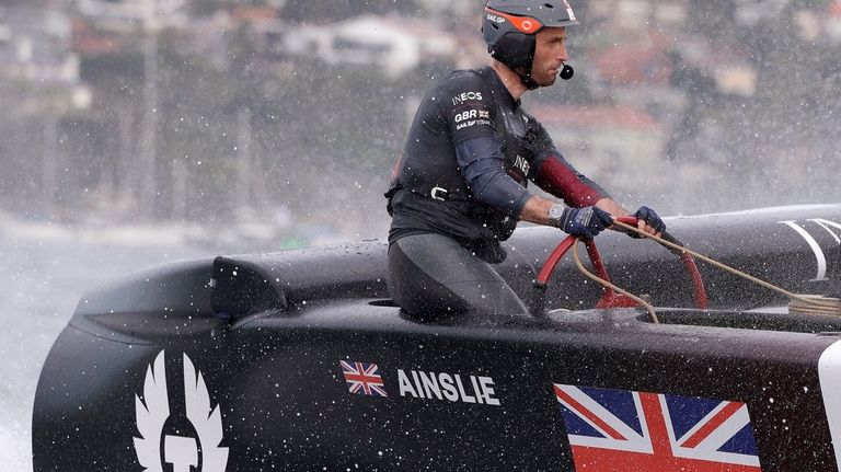 Skipper Ben Ainslie steers the boat as the British team...