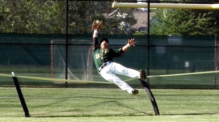 Ward Melville leftfielder Greg Coman (15) makes a catch over the...