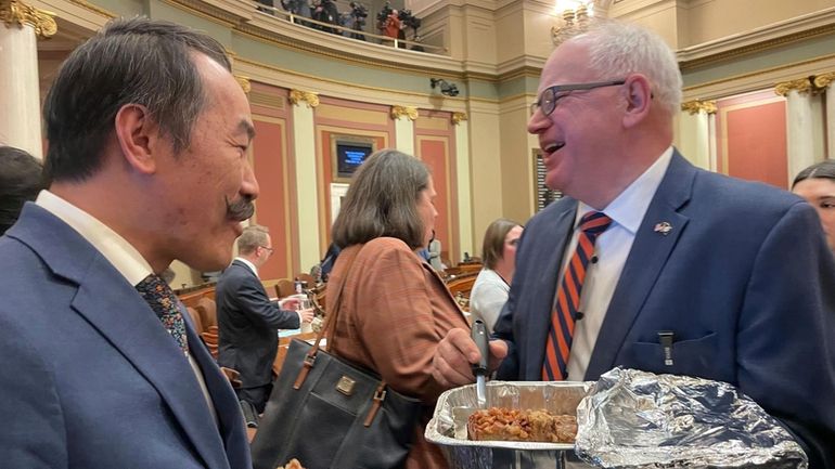 Minnesota Democratic Gov. Tim Walz serves an apple bar with...