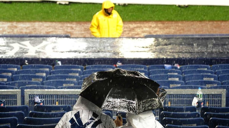 New York Yankees fans cover up as grounds crews cover...