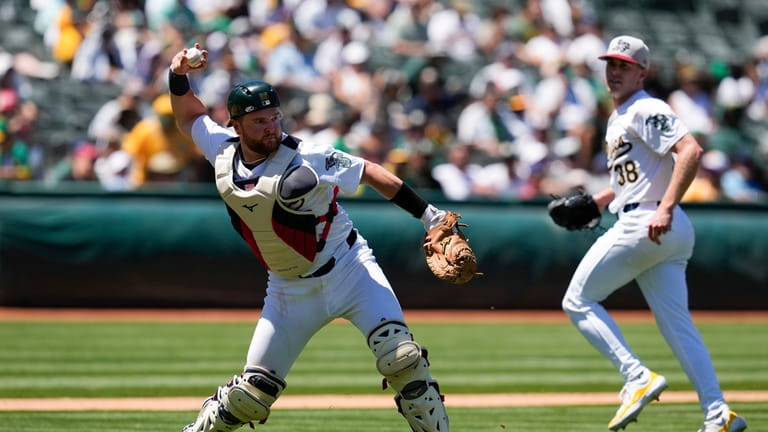 Oakland Athletics catcher Kyle McCann, left, throws to first for...