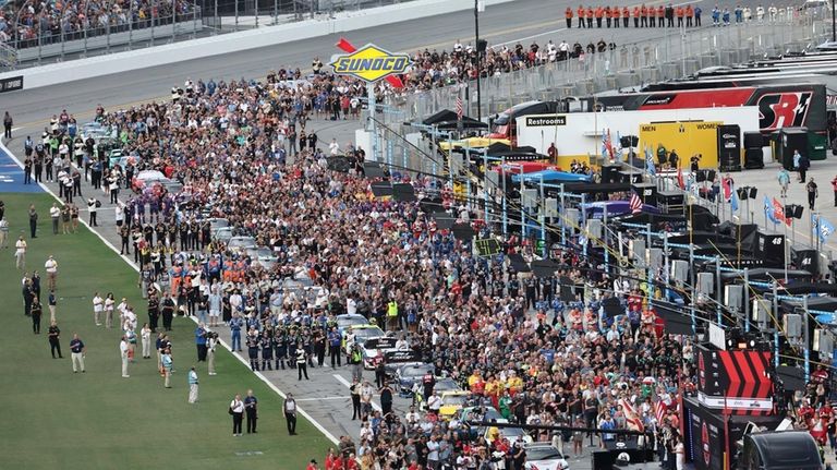 Drivers, crew members and guests stand on pit road for...