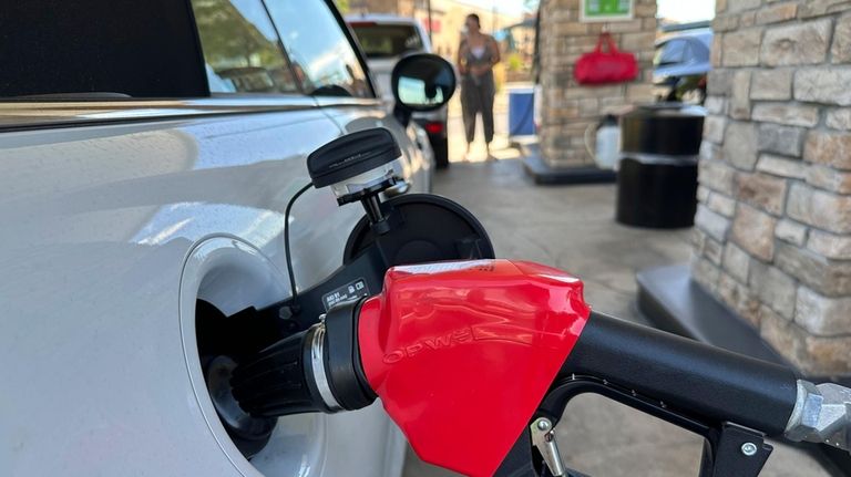 A motorist fills up the gasoline tank for a vehicle...