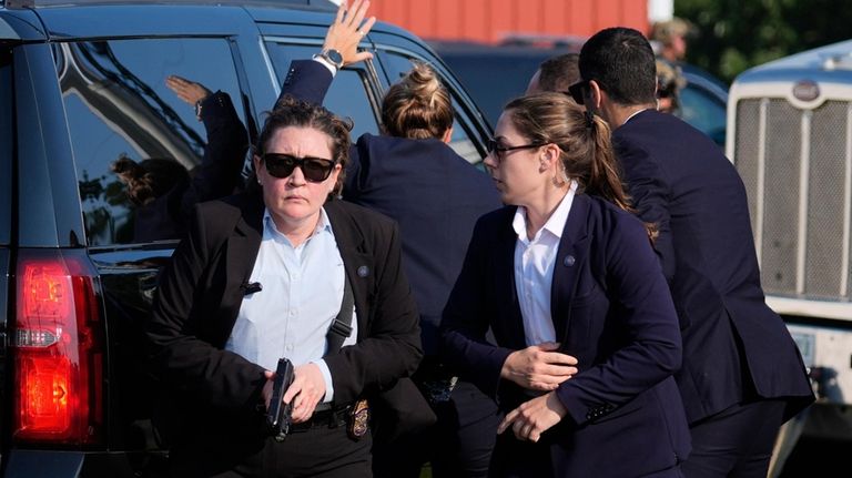 U.S. Secret Service agents surround the vehicle carrying Republican presidential...