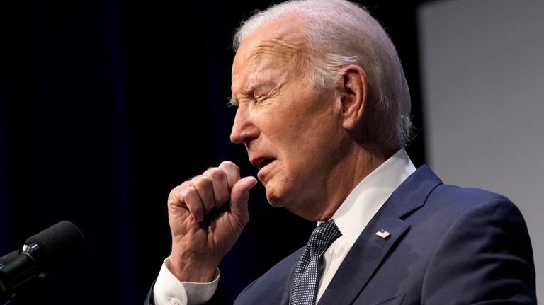 President Joe Biden coughs during an event with Rep. Steven...