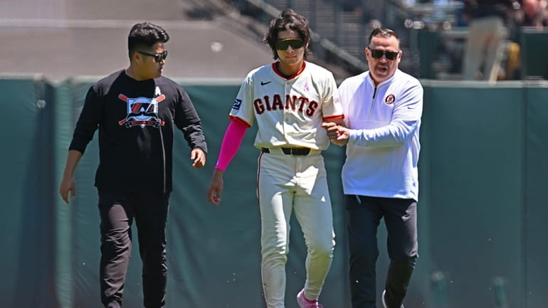 San Francisco Giants' Jung Hoo Lee, center, is escorted to...