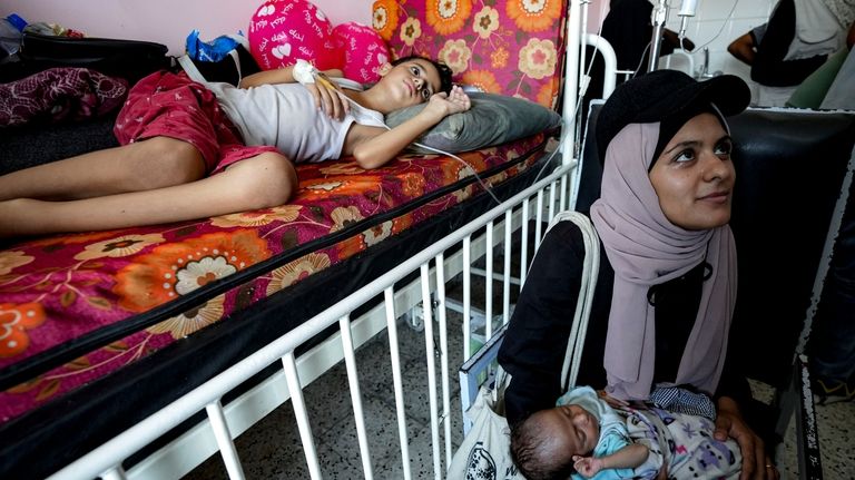 Palestinian children wait to receive a polio vaccination at a...