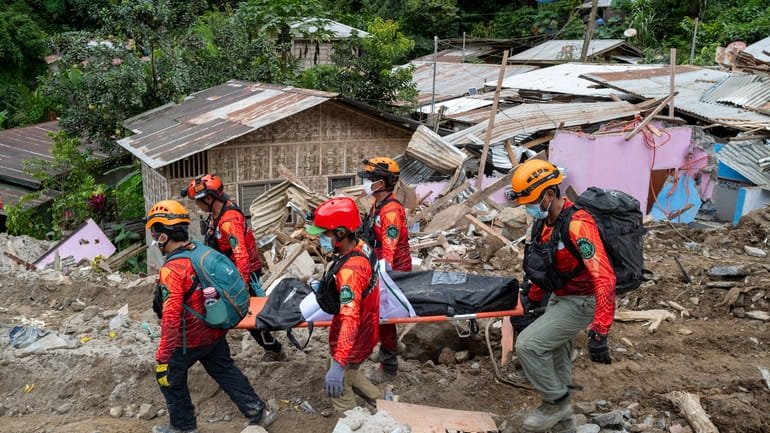 Rescuers carry a body from the landslide-hit village of Masara...