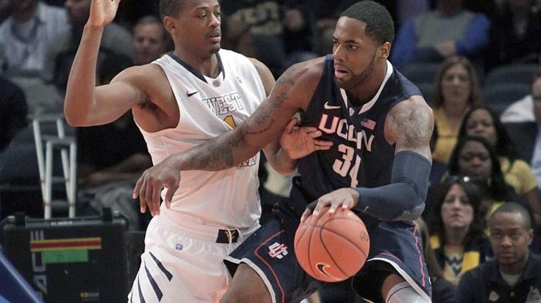 Connecticut's Alex Oriakhi, right, drives against West Virginia's Dominique Rutledge...