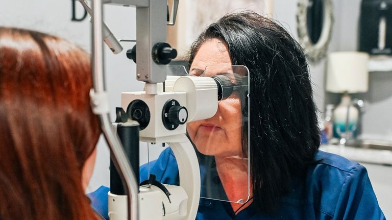 Optometrist Annette Webb checks a patient's eyes in her office...