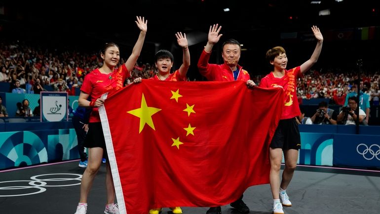 China team hold the flag of their country after defeating...