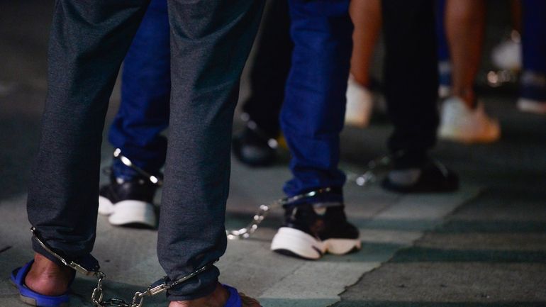 Colombian migrants stand in shackles as they prepare to enter...