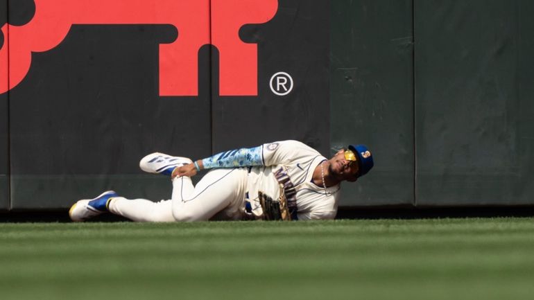 Seattle Mariners centerfielder Julio Rodriguez hold his leg after crashing...