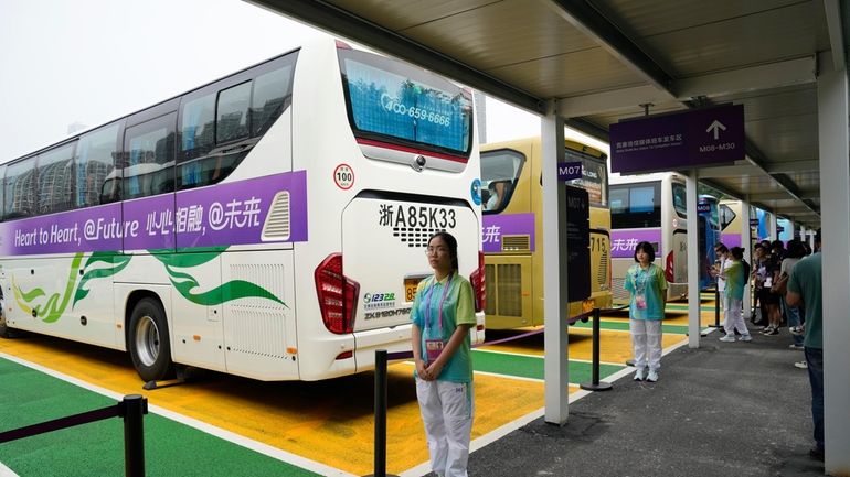 Chinese volunteers stand at a shuttle bus hub at the...