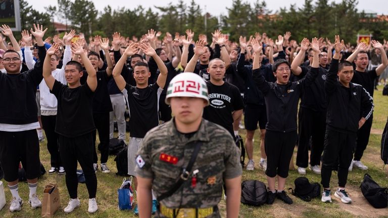 Standing behind a drill instructor, recruits wave to their family...