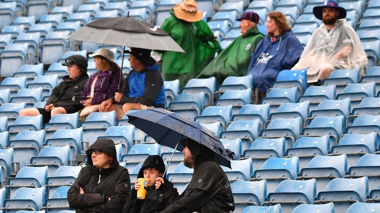 Baseball fans wearing ponchos wait during a rain delay prior to