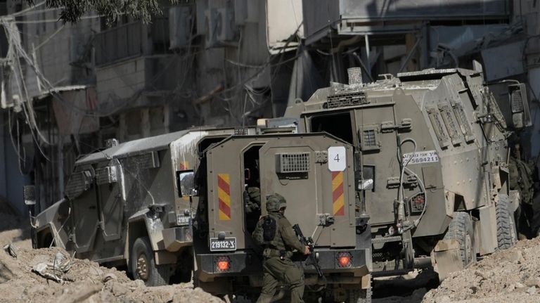 Members of Israeli forces patrol a street during a military...