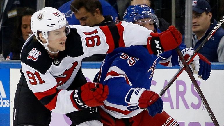 Dawson Mercer of the Devils tries to slow up Ryan Lindgren of...