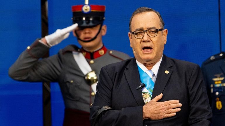 Guatemalan President Alejandro Giammattei sings the national anthem before giving...