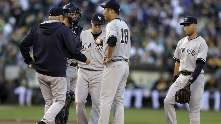 Yankees' Hiroki Kuroda is visited on the mound by pitching...