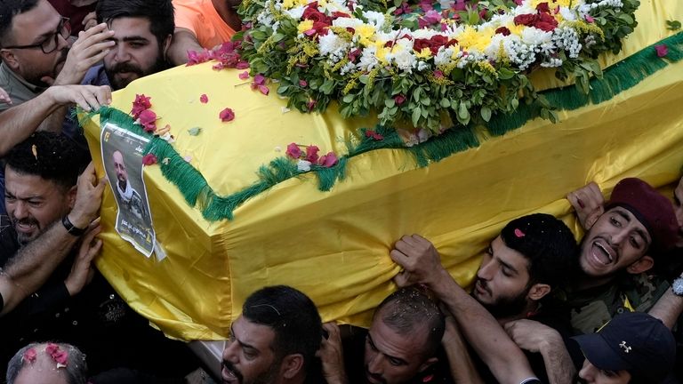 Hezbollah fighters carry one of the coffins of four fallen...